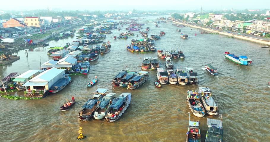 Bustling morning at Cai Rang Floating Market in Can Tho, Vietnam, where dozens of boats trade fresh fruits and agricultural products along the Mekong River. An authentic aerial view showcasing the vibrant river commerce and cultural heritage of the Mekong Delta.