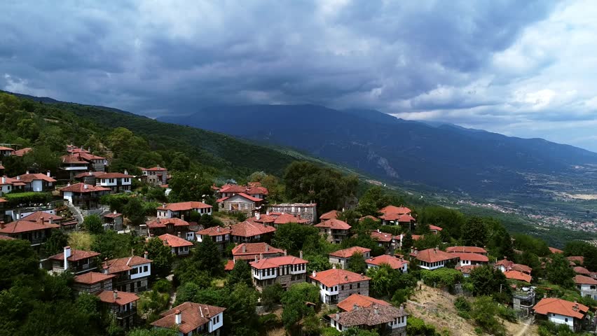 Aerial view of a traditional mountain village with red roofs and majestic Mount Olympus in the background