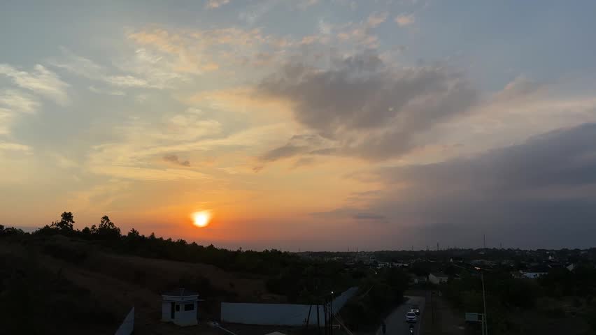 A beautiful sunset view with a golden-orange sky over the hills on the outskirts of the city.