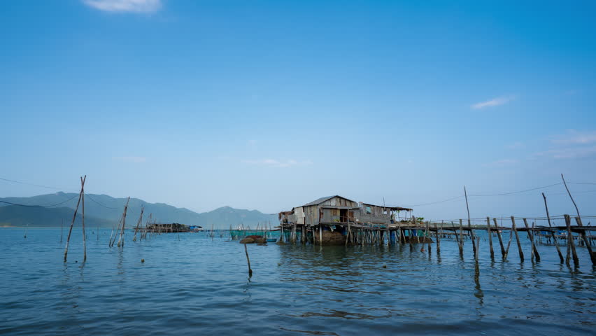 Timelapse of a traditional wooden fishing stilt house over calm sea water during late afternoon in Vietnam.