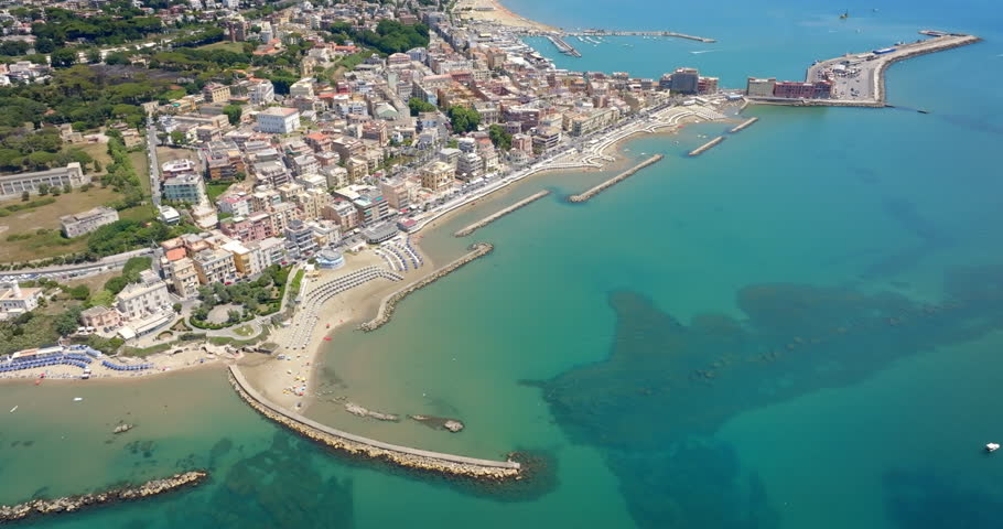 Aerial view of Anzio, near Rome, Italy, showing the historic port, breakwaters protecting the harbor, sandy beaches with sun umbrellas, and the city
