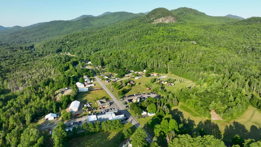 Aerial view of Elizabethtown, New York, surrounded by Adirondack Mountains, forests, and scenic countryside beneath clear summer skies.