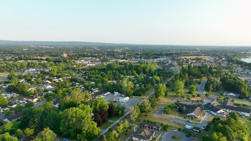 Aerial view of residential neighborhoods in Plattsburgh, New York, with Adirondack Mountains, green landscapes, and golden evening summer light.