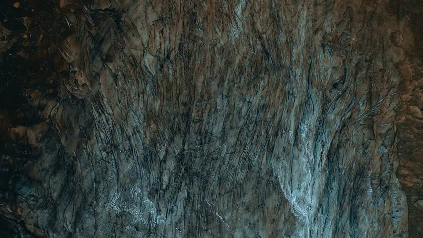 Top down view of textured glacial ice surface with dark soil and intricate frozen cracks motion.