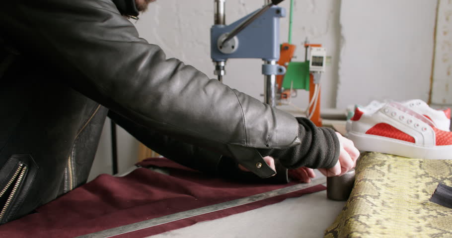 Shoemaker workshop. Handmade footwear. Unrecognizable master man hands using stationery knife sewing machine cutting material at shoes store.