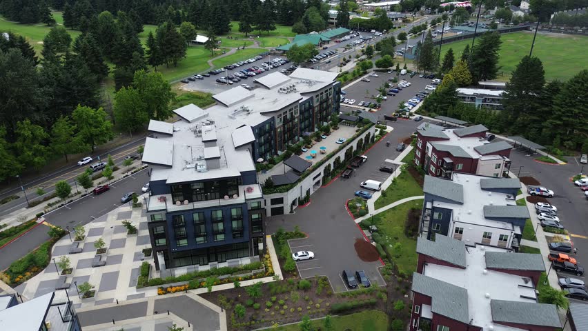 Architectural rooftop structures crown modern multi story mixed use buildings, suburbs Seattle. Paved plazas and parking spaces border the vibrant commercial corridors in Kent, Washington. USA