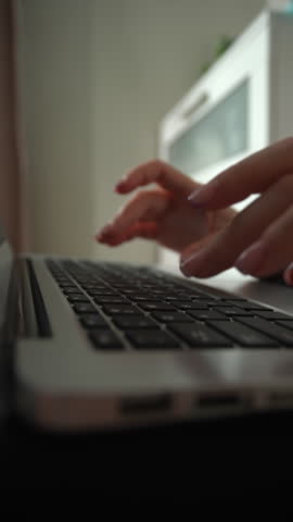 Side view of woman fingers with pink nail polish quickly typing on modern laptop keyboard working on project, communicating online, studying from home in sunny home office room, close-up, slow motion.