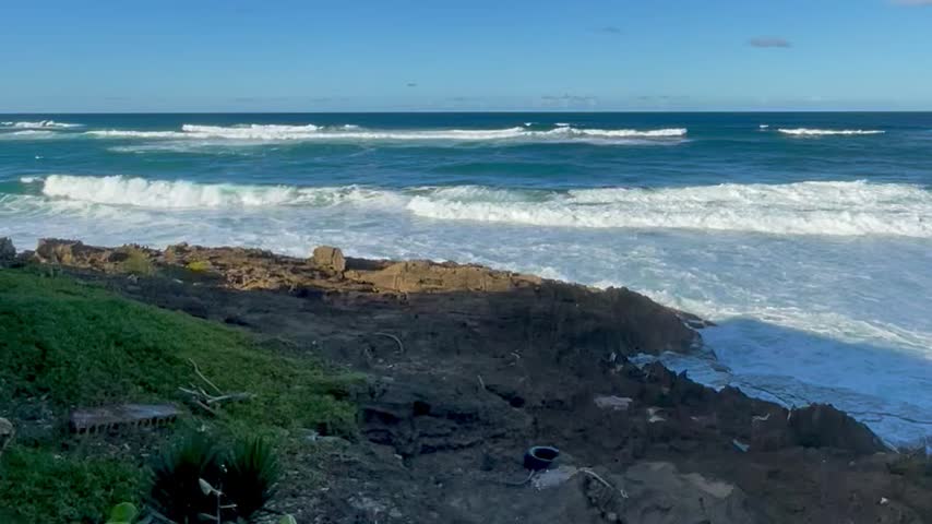 Powerful ocean waves crashing against a rocky tropical shoreline in Puerto Rico.