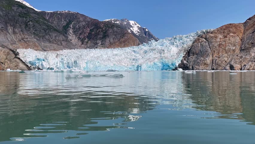 Scenic glacial ice wall floating on calm arctic water surface.