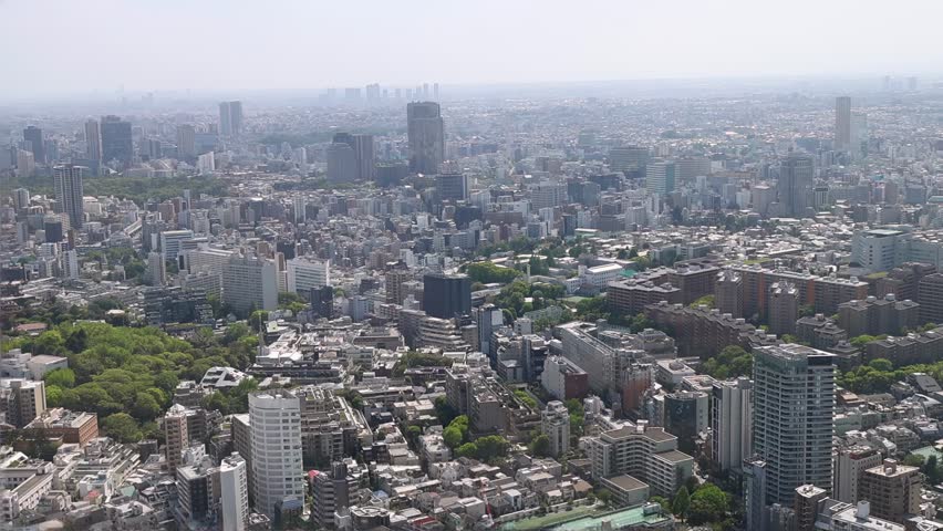 Tokyo skyline from a high viewpoint, showing dense residential and commercial buildings, busy road infrastructure and modern metropolitan landscape
