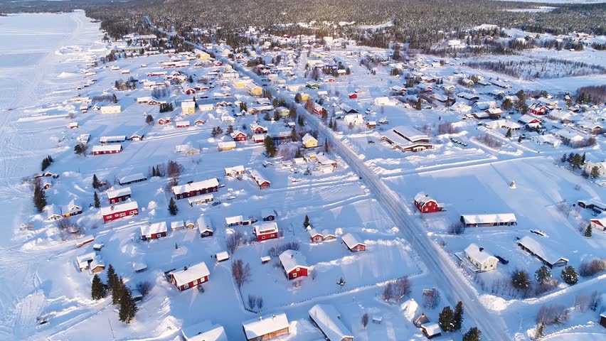 Winter village, snowy landscape, red houses, forest, sunset, aerial view.
