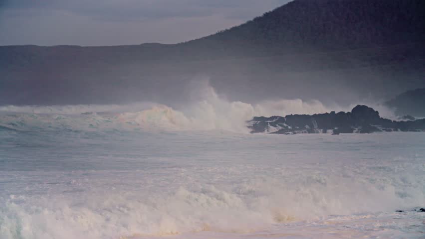 Powerful stormy waves crashing onto rocky coastal shoreline.