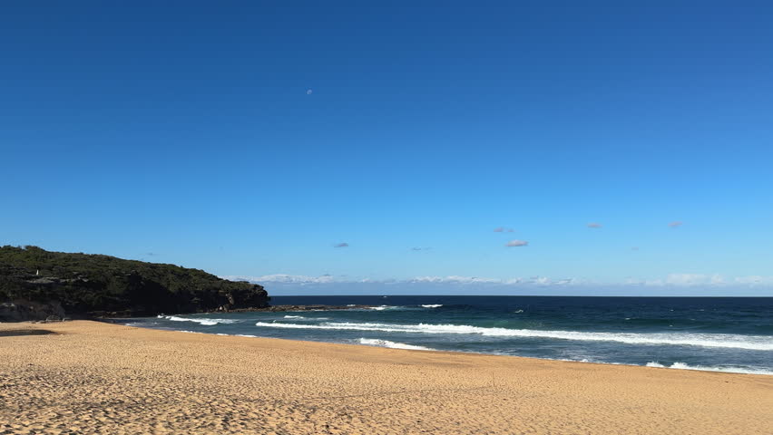 Scenic 4K Wide Shot of Ocean Waves Rolling on Golden Sand at Curl Curl Beach Sydney Australia, Slow Motion Beach Landscape with Moon in Clear Blue Sky