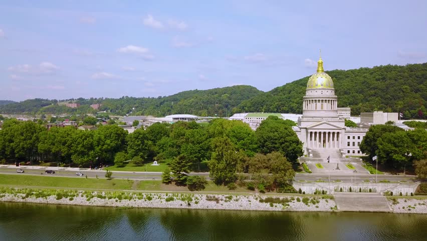 Slow panoramic drone footage of historic government house on riverbank.