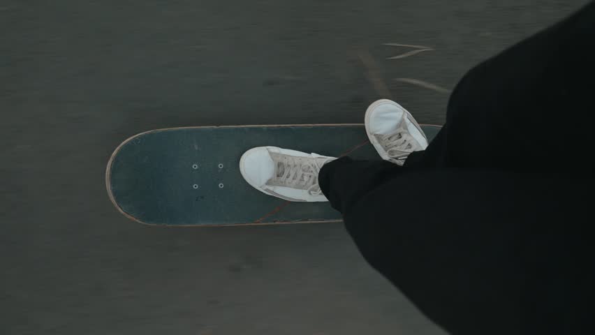 Person standing on skateboard with sneakers showing during nighttime urban setting