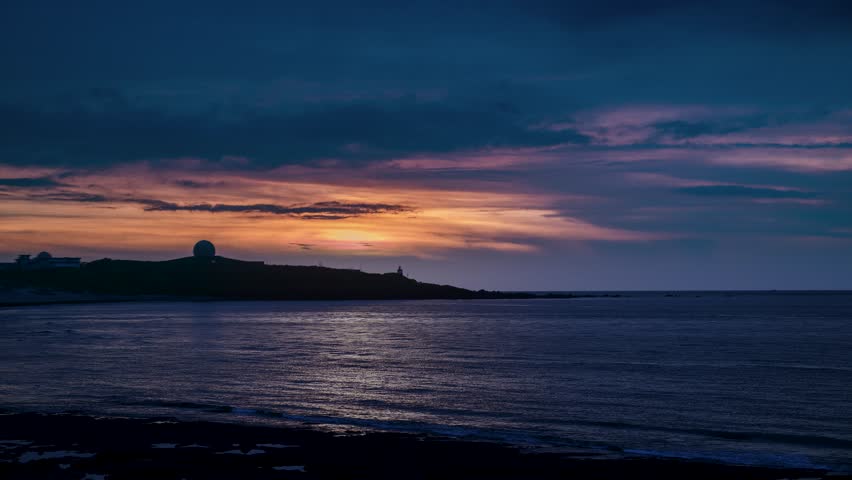 Beautiful sunset sky with orange and purple clouds over the silhouette of Fuguijiao Lighthouse and radar station on the coast of Shimen, Taiwan.