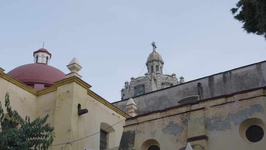 Old weathered facade of the san juan bautista parish church with its domes in coyoacan, mexico city