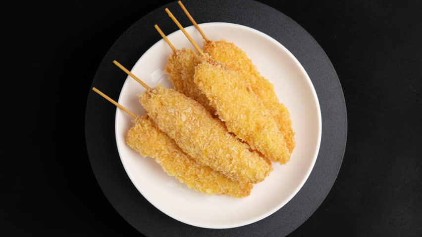 Fried chicken bites on a skewer or Popcorn chicken on a stick in white plate.Top view.
