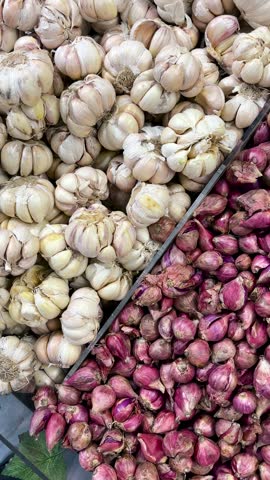 Neatly arranged piles of fresh garlic and shallots. Indonesian spices and seasonings.