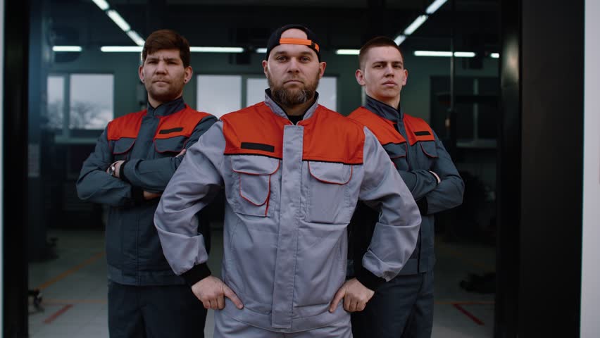 A team of professional automotive industry workers in uniform, with their hands folded 