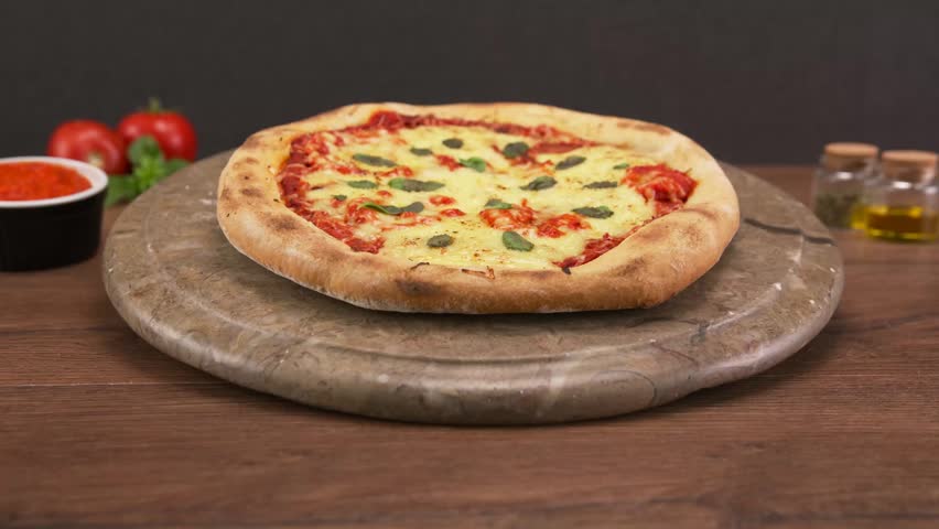 Delicious classic Italian pizza Margherita rotating on a wooden board.