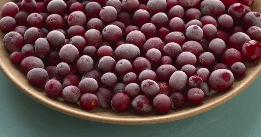 Close-up of raw, frozen cranberries on a plate. Turntable, slow, smooth rotation, 4K DCI.