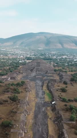Avenue of the Dead leading to the Pyramid of the Moon at Teotihuacan archaeological site framed by the Valley of Mexico landscape. Panoramic vertical aerial
