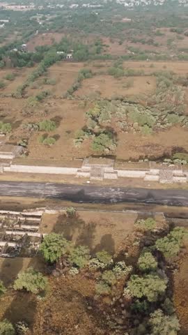 Calzada de los Muertos (Avenue of the Dead) at Teotihuacan archaeological site bordered by ancient ceremonial platforms and surrounding landscape, Mexico. Vertical aerial