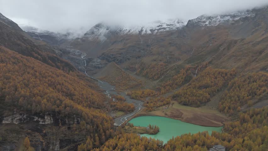 Dramatic mountain landscape with lake and orange trees.