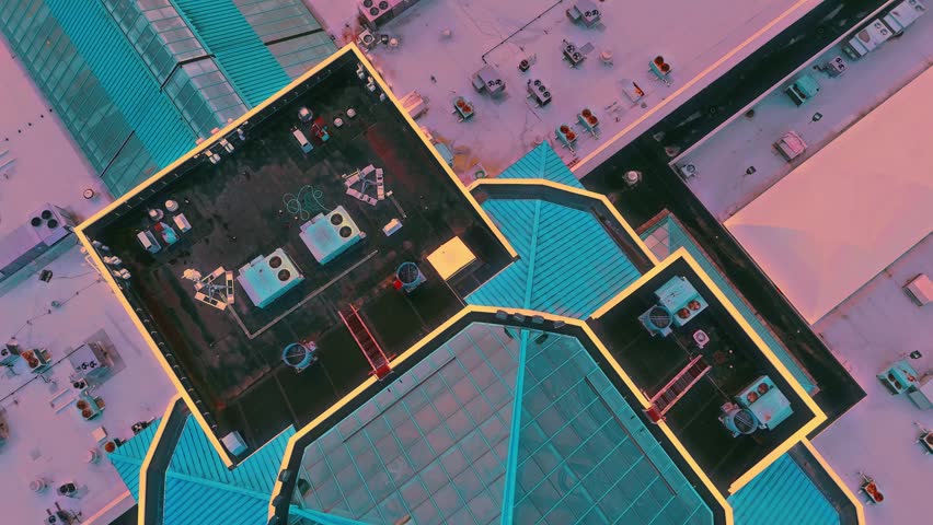 Passing over the top of a massive shopping mall and the apex crown of the enterprise as HVAC equipment can be seen littered across the roof of this building while the sun begins its descent on the other side of the lake just beyond the railroad tracks that wrap around the lakeshore.