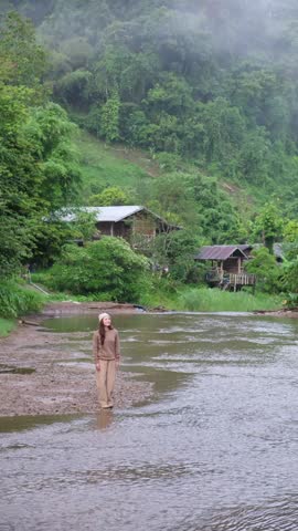A woman standing by the river in rural village and looking at a beautiful nature