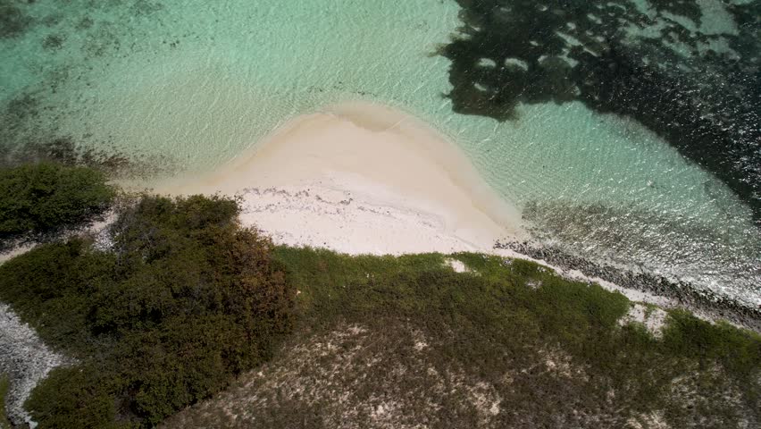 Drone tracking over a remote Caribbean island with queen conch shell mounds, white sand, and turquoise waters in Los Roques, Venezuela.4K Dlog