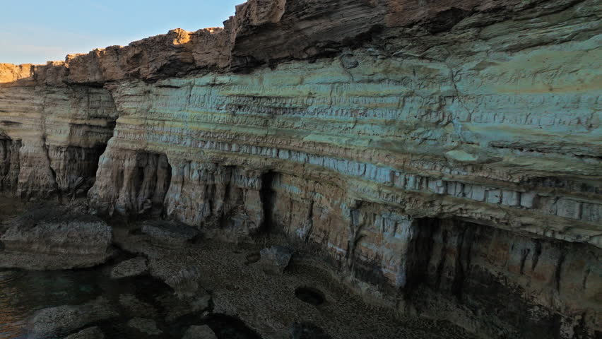 Aerial view of the Cape Cavo Greco Sea Caves in Cyprus. Layered limestone cliffs and sheltered cave formations create a striking Mediterranean landscape.