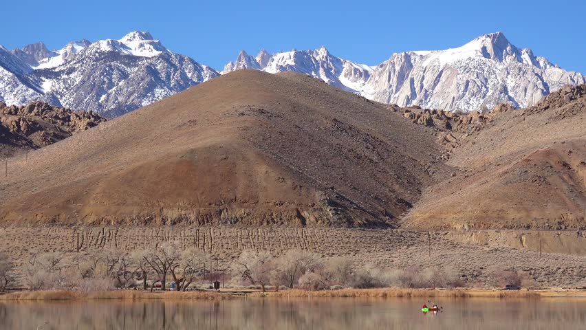 Kayaking on lake, mountains in background, peaceful nature scene.
