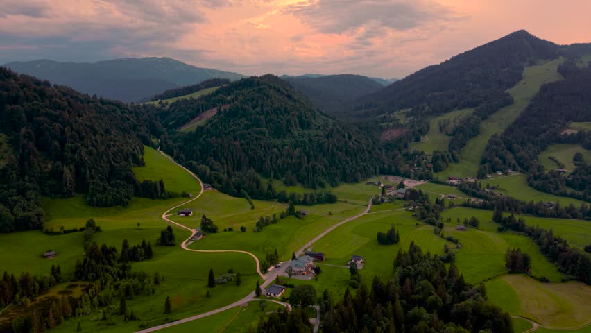 Golden hour sunset in Unken Heutal mountain valley, Austria. Green alpine meadows and forest. Aerial