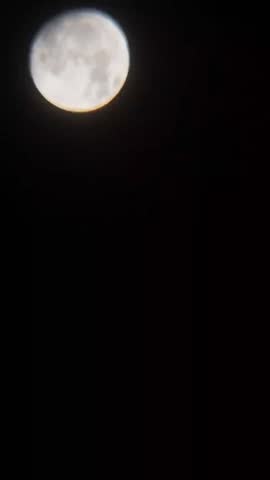 timelapse landscape view of a nearly full moon in the night sky
