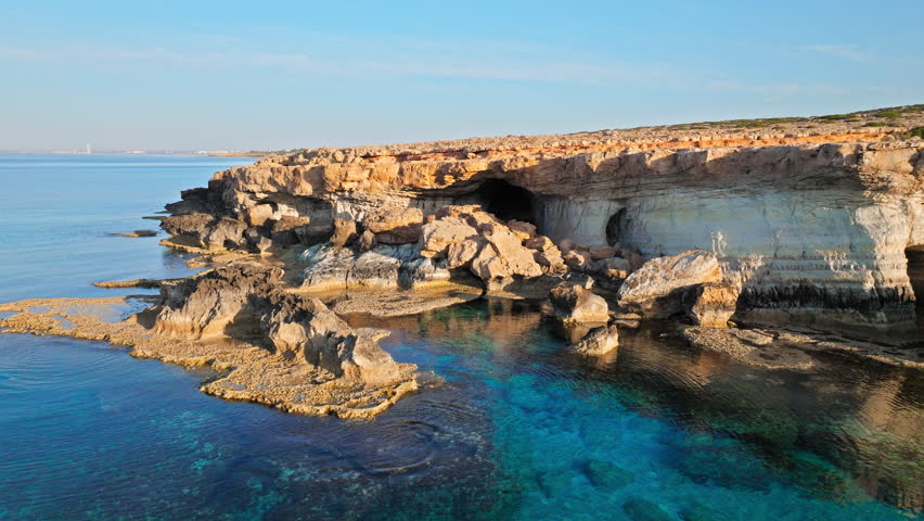 Aerial view of the Cape Cavo Greco Sea Caves in Cyprus. Rugged coastal rocks and eroded limestone formations create a dramatic shoreline.