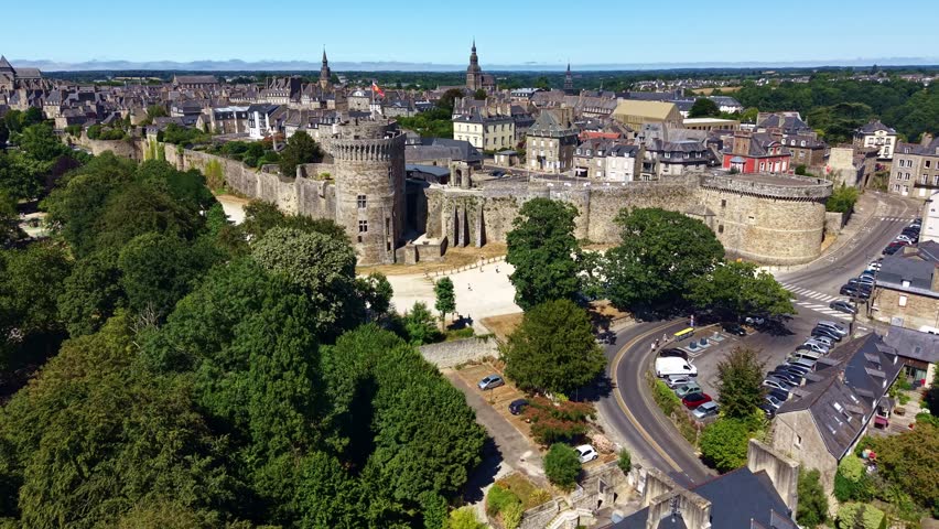 Drone flying toward Château de Dinan while ascending, revealing the medieval fortress, ramparts and historic town in Brittany, France.