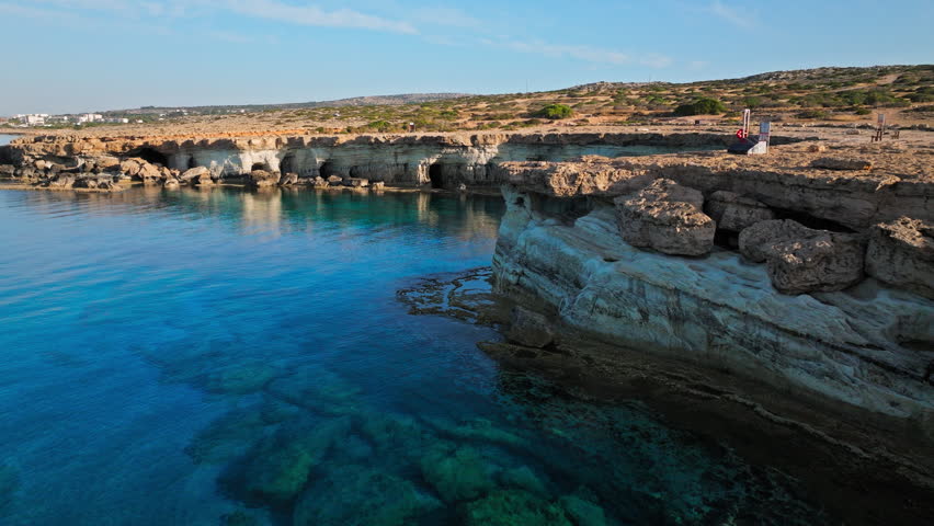 Aerial view along the Cape Cavo Greco Sea Caves in Cyprus. The cliff edge and deep blue water form a dramatic shoreline composition.