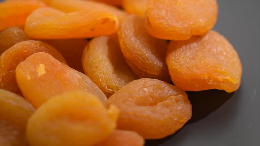 Apricot dried fruits on dark grey background. Ripe Organic Apricots fruit rotating. Dried apricots close-up. Close up. Heap of dried apricot. Vegan food, fiber. Border design