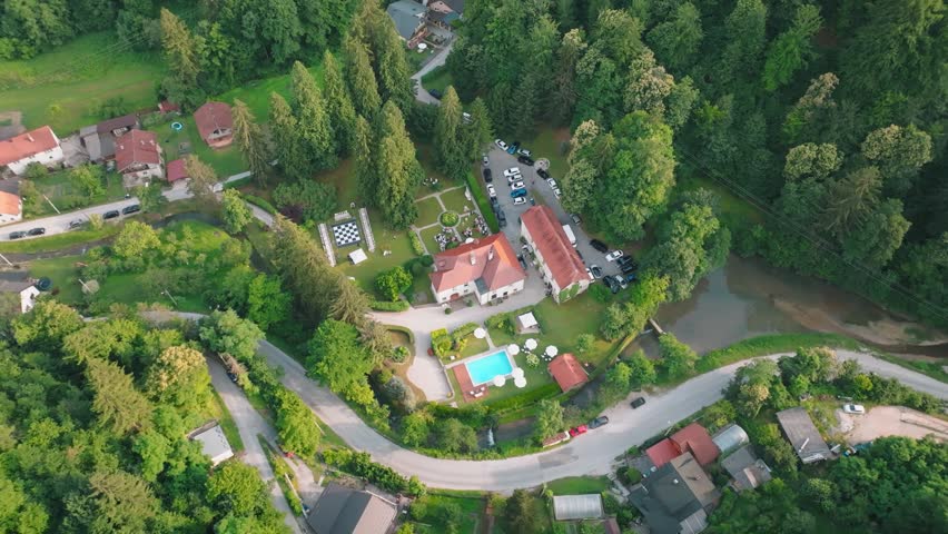 Aerial view of Kurija Hamor surrounded by lush forest, a swimming pool, and a winding road in Samobor, Zagrebacka zupanija, Croatia.