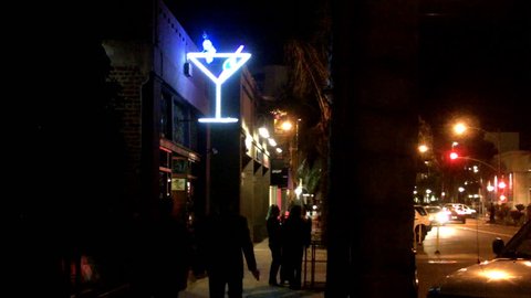 LONG BEACH, CA - FEBRUARY 21, 2013: Shot of (bar patrons) hanging out and walking past a downtown tavern circa 2013 in Long Beach. Businesses find creative ways to entice customers in a down economy.