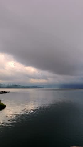 Dramatic Storm Clouds Gathering Over Calm Lake Water at Sunrise