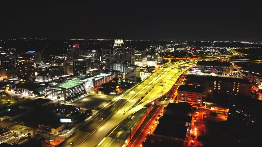 Aerial view of the illuminated Central Business District in Orlando at night with glowing skyscrapers and traffic on the highway, Orlando, Florida, United States.