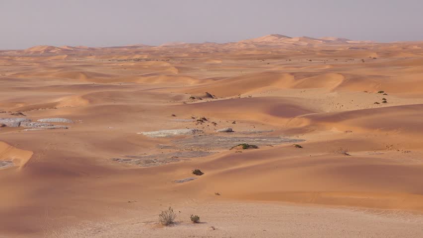 Vast desert sand dunes landscape under clear bright sky.