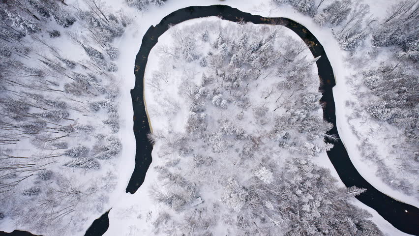 Aerial view of a river cutting through a peaceful winter landscape in Northern Michigan.