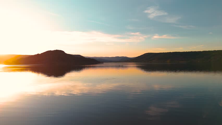 Calm mountain lake reflects colorful sunset sky across tranquil evening waters