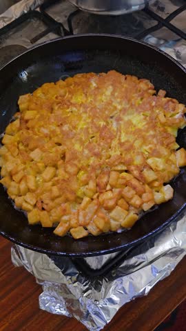 Fully cooked golden potato tortilla frying in a pan on the stove ready to be served