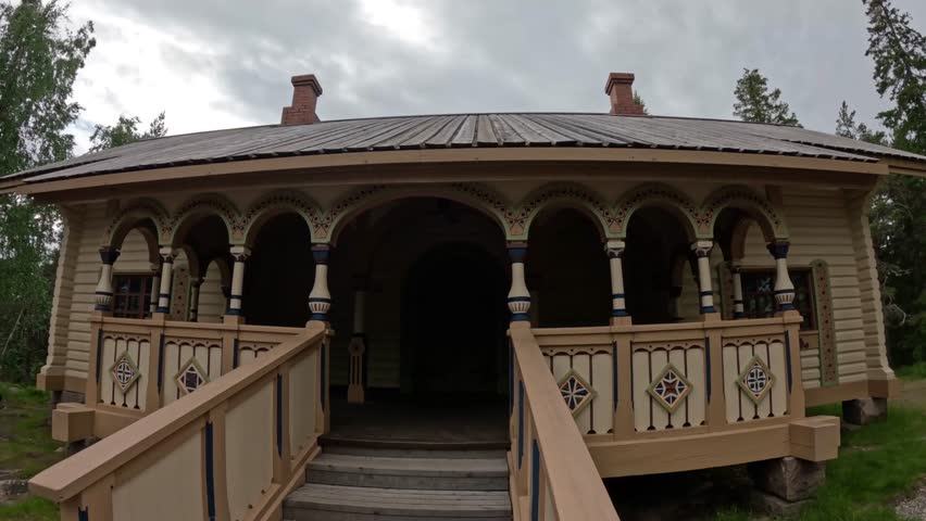 Static 4K view of the historic Keisarinmaja at Aavasaksa hill in Lapland, Finland, featuring ornate wooden architecture, stairs, and decorative details beneath cloudy skies.