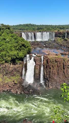 Daytime landscape of the upper and lower Iguazu Falls on the border of Brazil and Argentina, with powerful white water cascading over basalt rock formations and surrounded by lush greenery